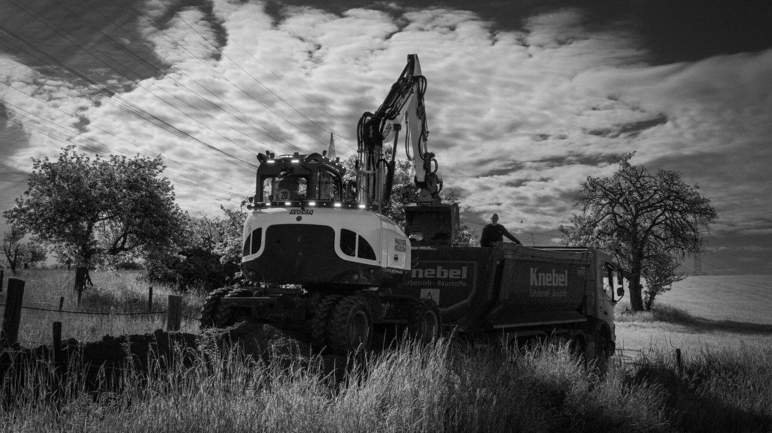 Bagger beim Beladen eines Lkw während der Erdarbeiten auf einer Baustelle.