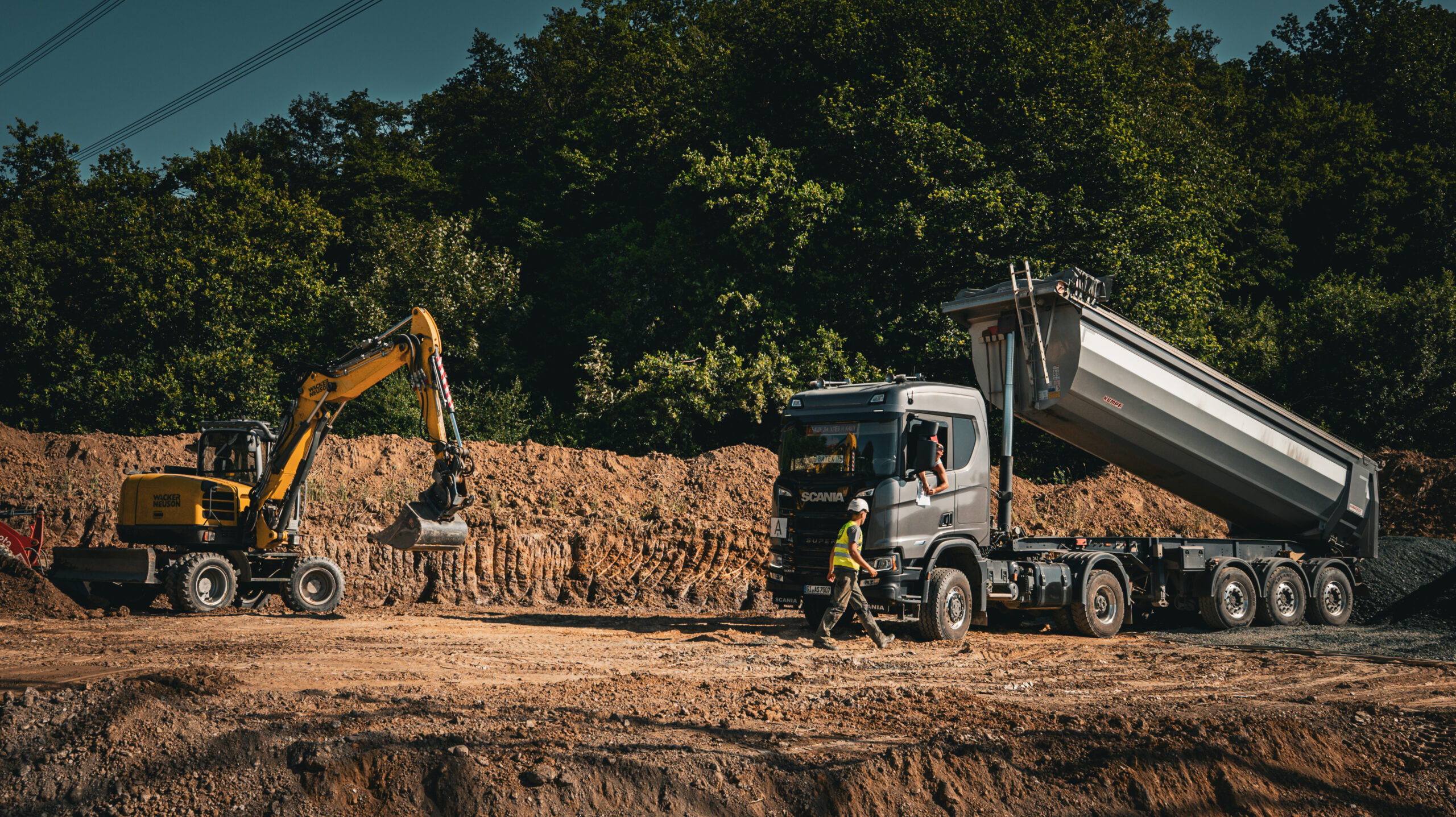 Bagger, Lkw und Mitarbeiter bei Erdarbeiten auf einer Baustelle von LS Forst.